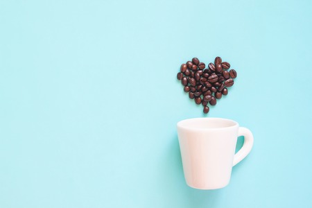 Coffee poster advertisement. White cup with coffee beans arranged in heart shape on pastel colour...