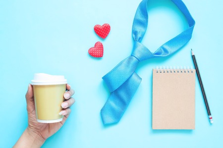 Creative flat lay of Father's Day concept. Necktie, notebook and woman hand holding coffee cup on...