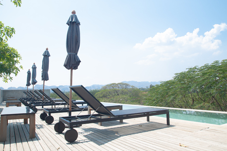 Kanchanaburi, Thailand - February 20, 2019 : Modern and simply design chaise lounge and swimming pool on the hotel roof top with mountain viewのeditorial素材
