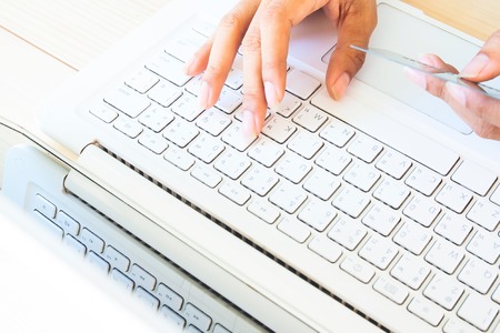 Cropped shot of a young woman using notebook computer and credit card, woman's hands using laptop computer for online shopping. Shopping online concept or using technology.の写真素材
