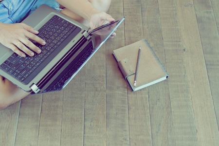 Young male using laptop computer sitting on wooden floor. Writer or freelancer with technology. Lifestyle conceptの写真素材