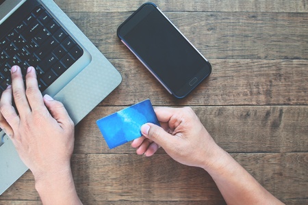 Blank screen smartphone for application mock up with man using credit card and laptop computerの写真素材