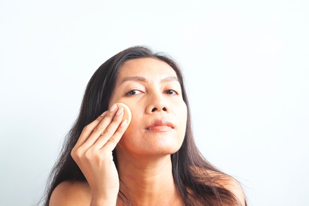 Asian woman looking at camera and applying foundation powder on her face. Beauty conceptの写真素材