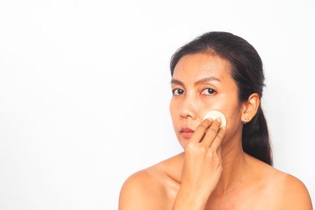 Asian woman looking at camera and applying foundation powder on her face. Beauty conceptの写真素材