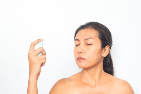 Beautiful Asian woman spraying mineral water on her face. Beauty and health conceptの写真素材