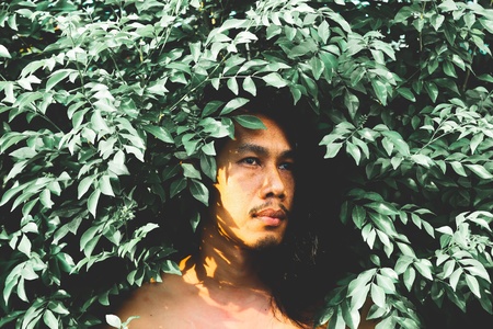 Handsome man with long hairstyle posing with plant. Vintage and film filter styleの写真素材