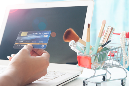 Hands holding credit card and using laptop computer. Beauty online shopping, E-payment or internet bankingの写真素材