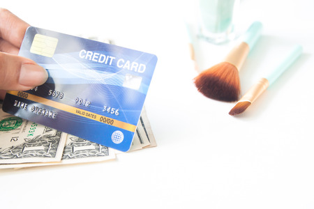 E-payment, E-business concept. Woman hand holding plastic credit card with beauty items on white backgroundの写真素材