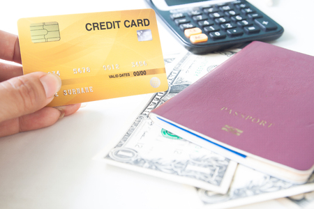 Woman hand holding plastic credit card with passport and dollar bills. Business concept. Travel or bookingの写真素材