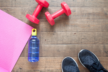 Creative flat lay of workout concept. Fitness equipment, water bottle and sport shoes on wooden floorの写真素材