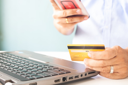 Man hands using laptop and mobile phone holding credit card. E-payment and technology conceptの写真素材