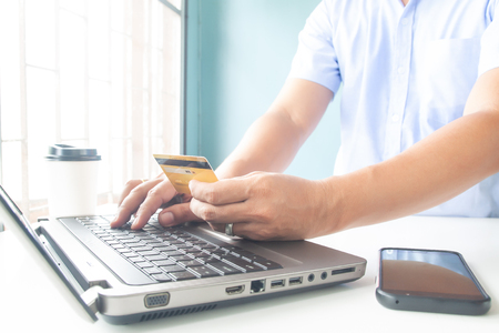Online payment, Man's hands holding a credit card and using laptop for online shoppingの写真素材