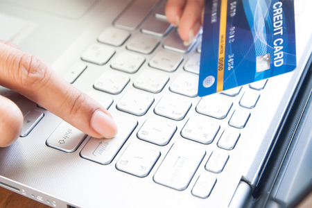 Woman hand holding plastic credit card and push enter button. Business and e-payment concept.の写真素材