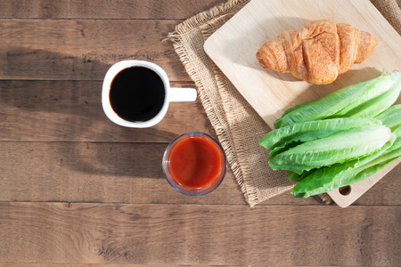 Coffee white cup, tomato juice croissants on retro wooden background. Flat lay. Breakfast conceptの写真素材