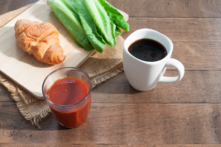 Tomato juice, black coffee, croissant and vegetable on rustic wooden table. Breakfast conceptの写真素材