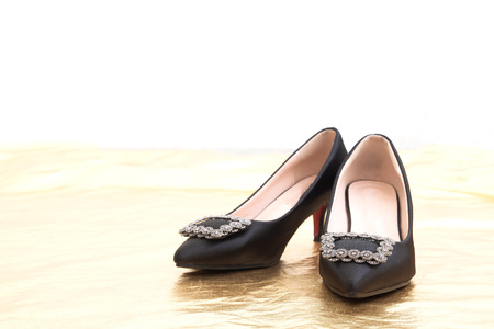 Pair of beautiful high heels shoes with copy space on golden and white backgroundの写真素材