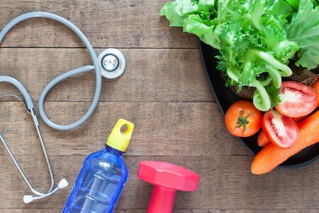 Healthy concept, stethoscopes and fresh vegetables on wooden background.の写真素材