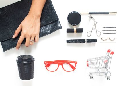 Woman hand holding trendy purse with woman accessories and cosmetics on white background. Beauty or Business conceptの写真素材