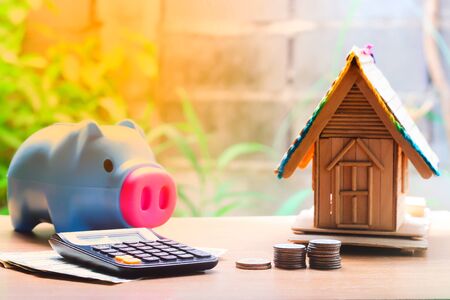 Coin stacks, house model, calculator and piggy bank, savings plans for housingの写真素材