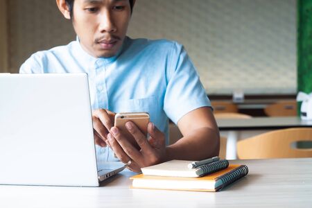 Asian guy using smart phone and laptop computer for marketing content. Online marketing. Business and technology conceptの写真素材
