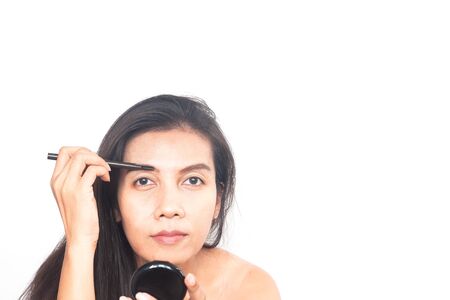 Portrait of 40s Asian woman applying eyebrow. Make up and Beauty concept. Anti aging and surgery.の写真素材