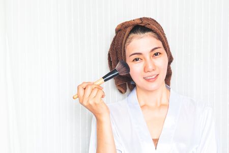 Facial Makeup. Beautiful Asian Female Model Putting Blush With Cosmetic Brush. Portrait Of Attractive Healthy 30+ Year Old Woman With Pure Clean Skin And Natural Make-Up. Beauty Concept.の写真素材