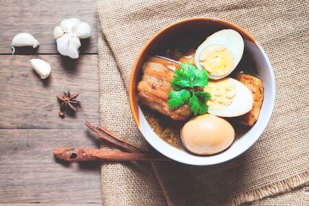 Stewed eggs and pork or eggs and pork in brown sauce in bowl with spices on wooden table. Top viewの写真素材