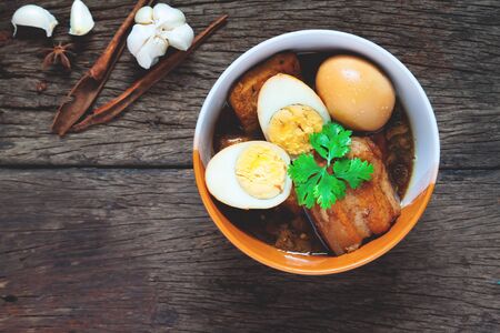 Stewed eggs and pork or eggs and pork in brown sauce in bowl with spices on wooden table. Top viewの写真素材