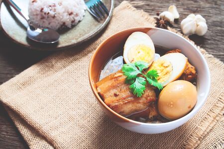 Stewed eggs and pork or eggs and pork in brown sauce in bowl with spices on wooden table. Top viewの写真素材