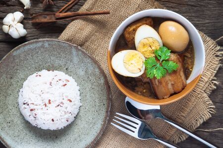 Stewed eggs and pork or eggs and pork in brown sauce in bowl with rice on wooden table. Top viewの写真素材