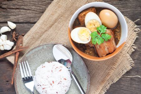 Stewed eggs and pork or eggs and pork in brown sauce in bowl with rice on wooden table. Top viewの写真素材