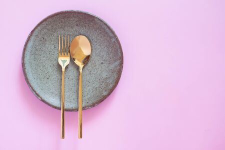 Table setting, Ceramic dishware, spoon and fork on pink pastel color backgroundの写真素材
