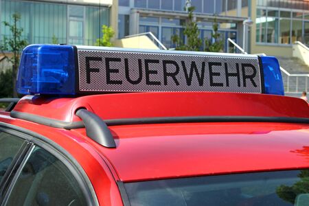 german red fire brigade car with blue light in front od a school, close-upの写真素材