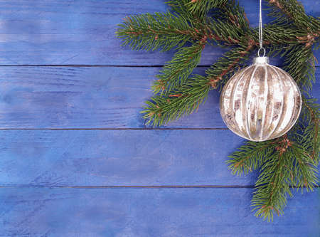 background with silver Christmas ball with spruce branches on wood planksの写真素材