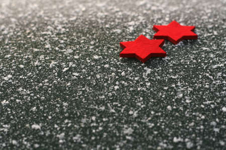 two red felt stars lying on asphalt with snowflakesの写真素材