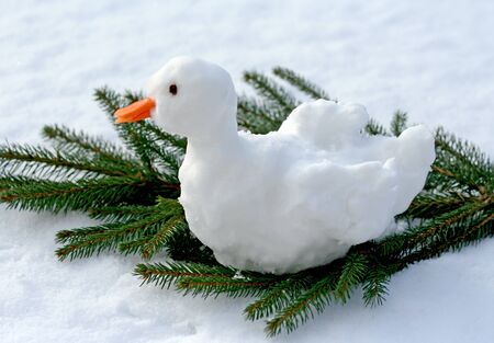 Christmas goose made of snow sitting on a fir branch, sunlightの写真素材
