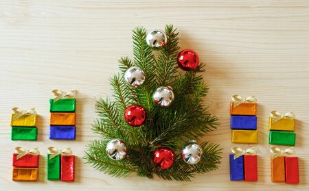 Christmas greeting card with a Christmas tree and many wrapped gifts on bright wooden table