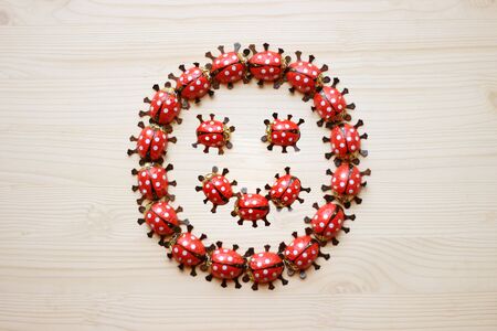 greeting card with a smiley, formed by chocolate ladybugs, on bright wood