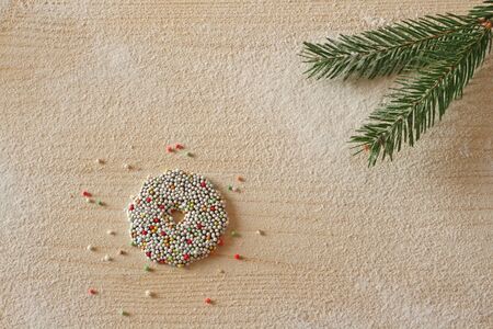 Christmas background with sprinkled chocolate wreath and pine branch on wood, covered with sugar, like snowの写真素材