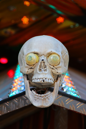laughing skull with eyes at the entrance of a ghost train, multi colored light in the backの写真素材