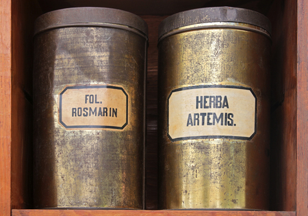 close-up of old tin cans with the medicinal herbs rosemary leaves and wormwood in a wooden shelfの写真素材