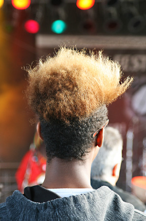 rear view of a young african man with a striking afro hairdo at a music event, looking at the stageの写真素材