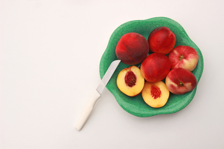 summer fruits, peaches and nectarines in a green bowl, one cut in halfsの写真素材