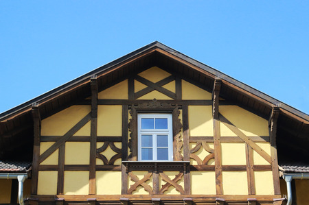gable of a rustic yellow half-timbered house in front of blue skyの写真素材