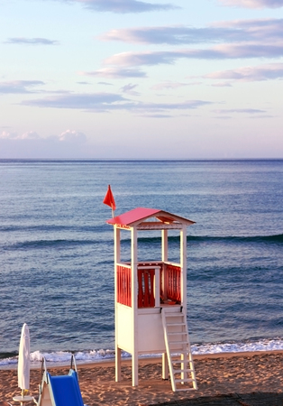 sunset at an italian beach with a red and white lifeguard watchtowerの写真素材