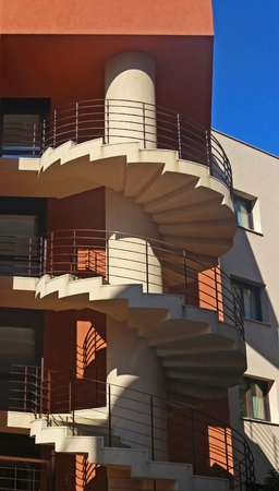 external spiral staircase of am orange colored residential building, blue skyの写真素材