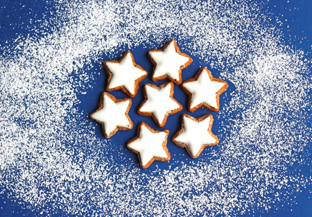 blue and white christmas background with a pattern of star cookies and powdered sugar as snow