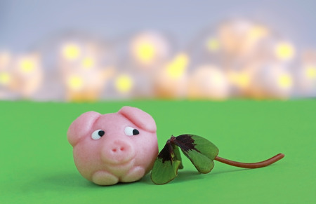 happy new year, marzipan pig and four-leaved clover on green, lights in the backの写真素材