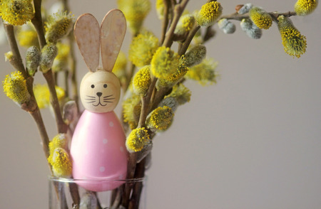 cute Easter bunny sitting between a bunch of blooming willow branchesの写真素材