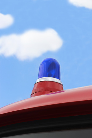 blue light on an old fire engine in front of blue and white skyの写真素材